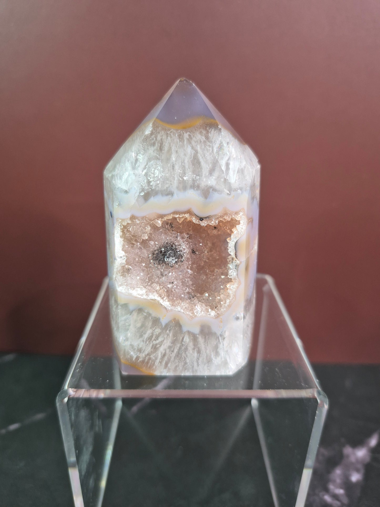 Crystal with a brown interior on a clear stand against a blurred background