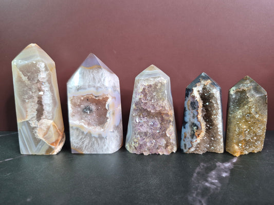 Five crystal towers with varying geode structures on a dark surface and brown background